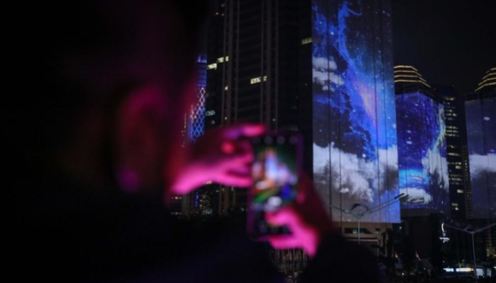 Warga menyaksikan penampilan video mapping dengan tema KTT ASEAN 2023 di Jalan Jendral Sudirman, Jakarta.
