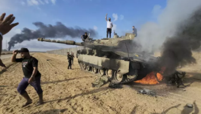 Warga Palestina merayakan di sekitar tank Israel yang hancur di dekat pagar Jalur Gaza di Khan Younis selatan pada Sabtu, 7 Oktober 2023.